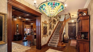 A grand foyer with a wooden staircase, ornate mirrors, and a piano. - The Reserve at Hot Springs (Hot Springs)