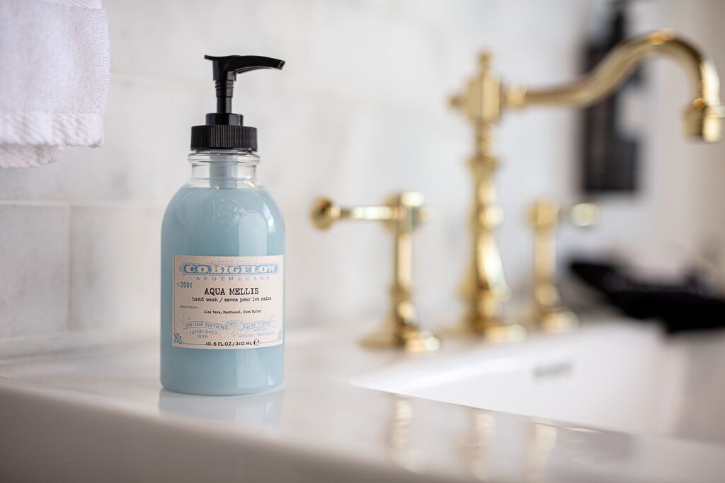 A bathroom with a blue hand soap bottle labeled 'Aqua Melis' on a white sink.
