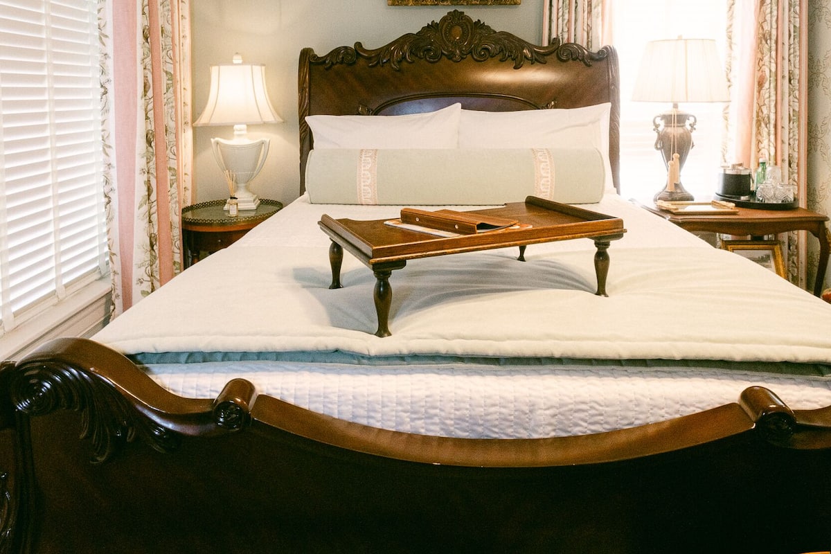 A neatly made bed with a wooden headboard, two bedside tables with lamps, and a framed picture on the wall.