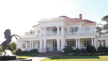 A large white building with a red roof, multiple balconies, and a statue of a horse.