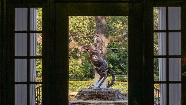 A doorway with a stained glass chandelier, a stone fountain, and a sculpture of a horse. - The Reserve at Hot Springs (Hot Springs)