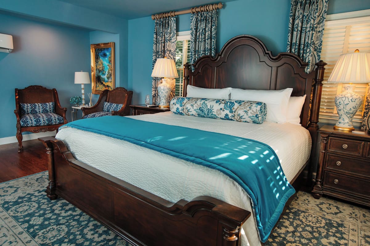 A bedroom with a large bed, wooden headboard, and matching nightstands.