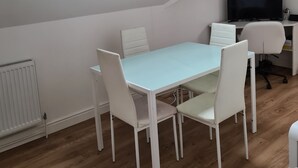 A room with a sloped ceiling, a skylight, a dining table with chairs, a TV, and a radiator. - 2-Bed Loft Apartment for 5ppl with private parking (Beckenham)