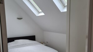 A bedroom with a bed, a nightstand, and a skylight. - 2-Bed Loft Apartment for 5ppl with private parking (Beckenham)