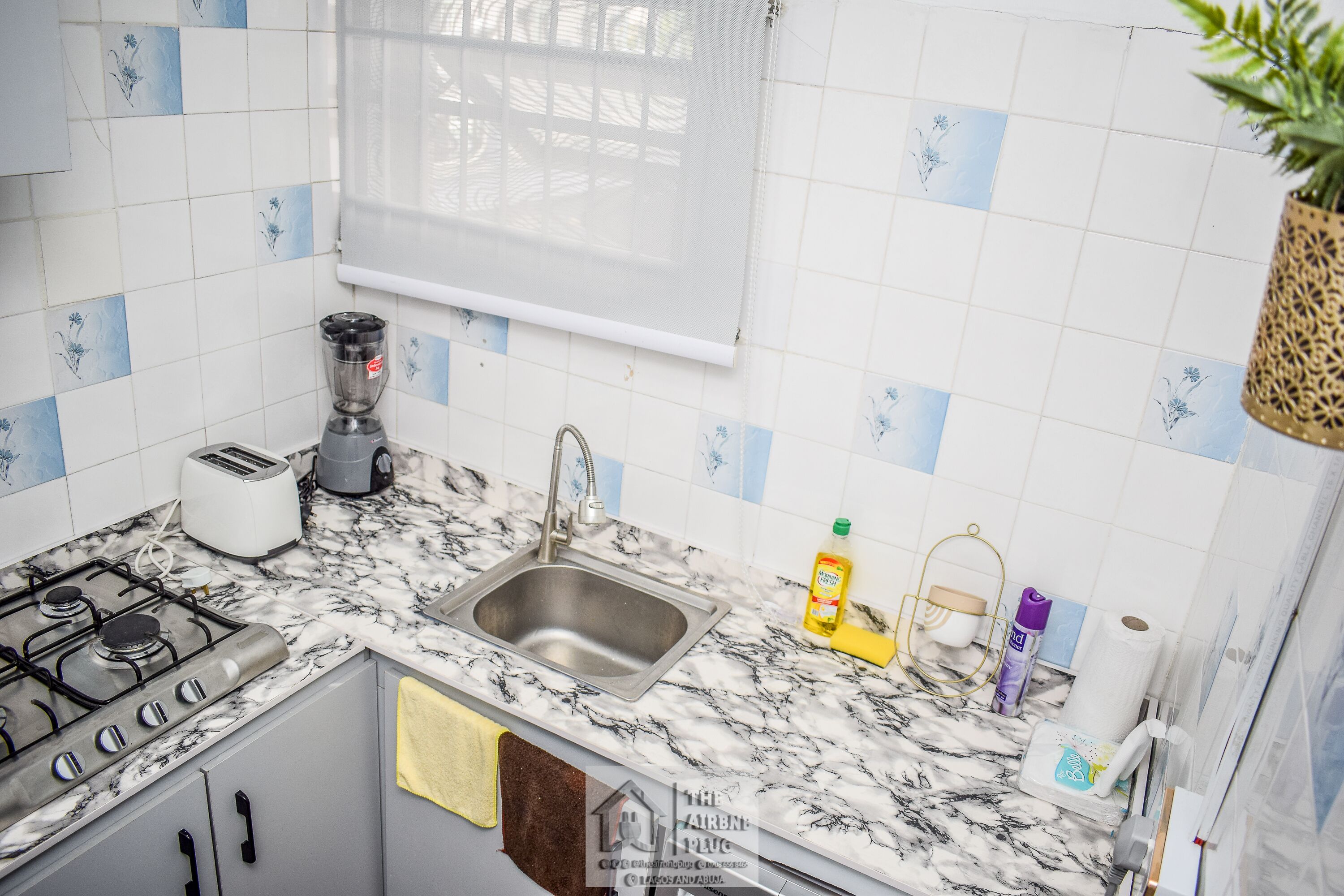 Eine Küche mit einem Gaskochfeld, einem Spülbecken, einem Toaster und einem Mixer.