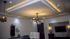 Un salon moderne avec un décor au plafond original, un grand miroir, un téléviseur et une enseigne indiquant « The Airborne House ».