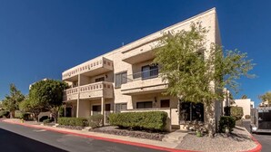 A multi-story building with a flat facade, balconies, and a red curb.