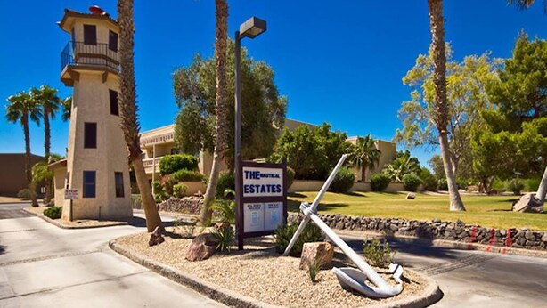 A sign for The Nautical Estates with a lighthouse and palm trees in the background.