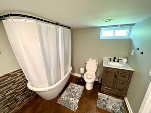 Ein Badezimmer mit Duschvorhang, Toilette, Waschbecken und Holzboden.