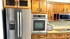 Une cuisine avec des armoires en bois, un réfrigérateur en acier inoxydable, un four et un four à micro-ondes.