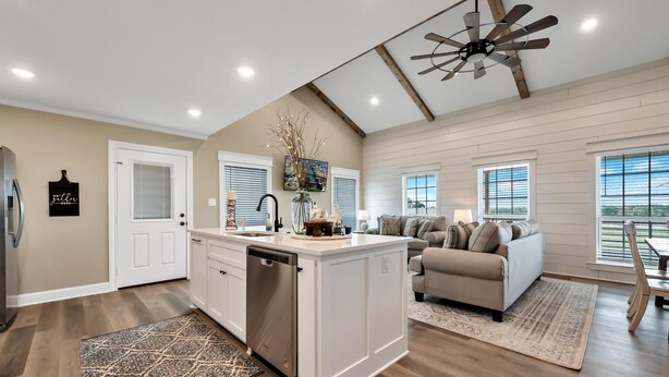 A spacious kitchen with a central island, a dining area with a wooden table and chairs, and a living room with a sofa and a ceiling fan. - Farmhouse Charm - Waco/Magnolia/Baylor (Waco)