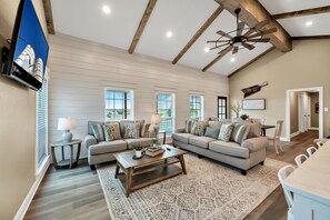 Relax in this stylish living room with a high ceiling, two sofas, and a large television.