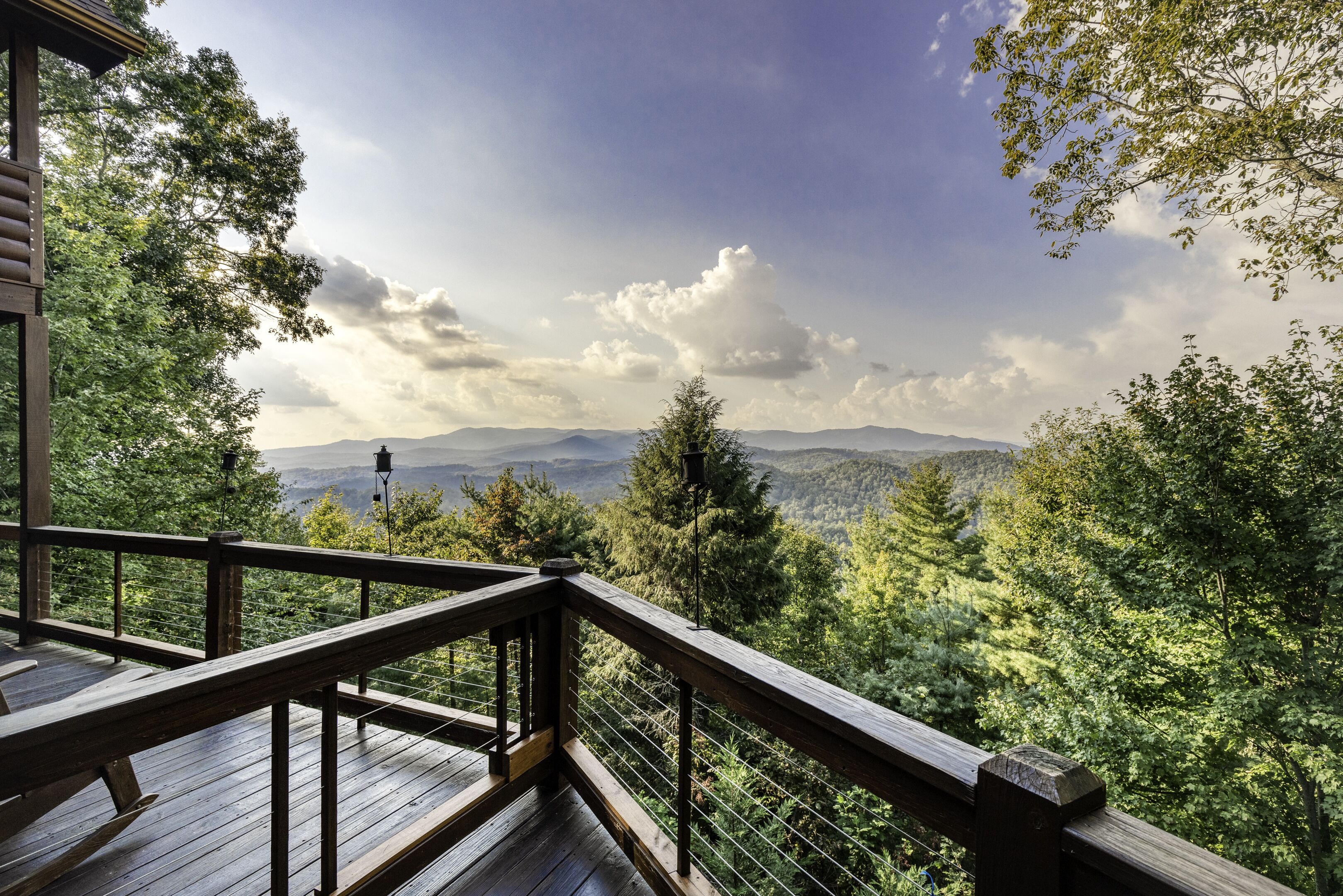 Um deck de madeira com guarda-corpo, com vista para uma paisagem montanhosa.