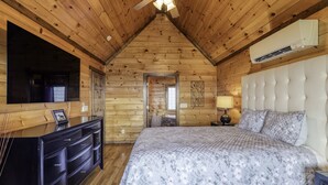 Un dormitorio tipo cabaña de madera con cama, cómoda y ventilador de techo.
