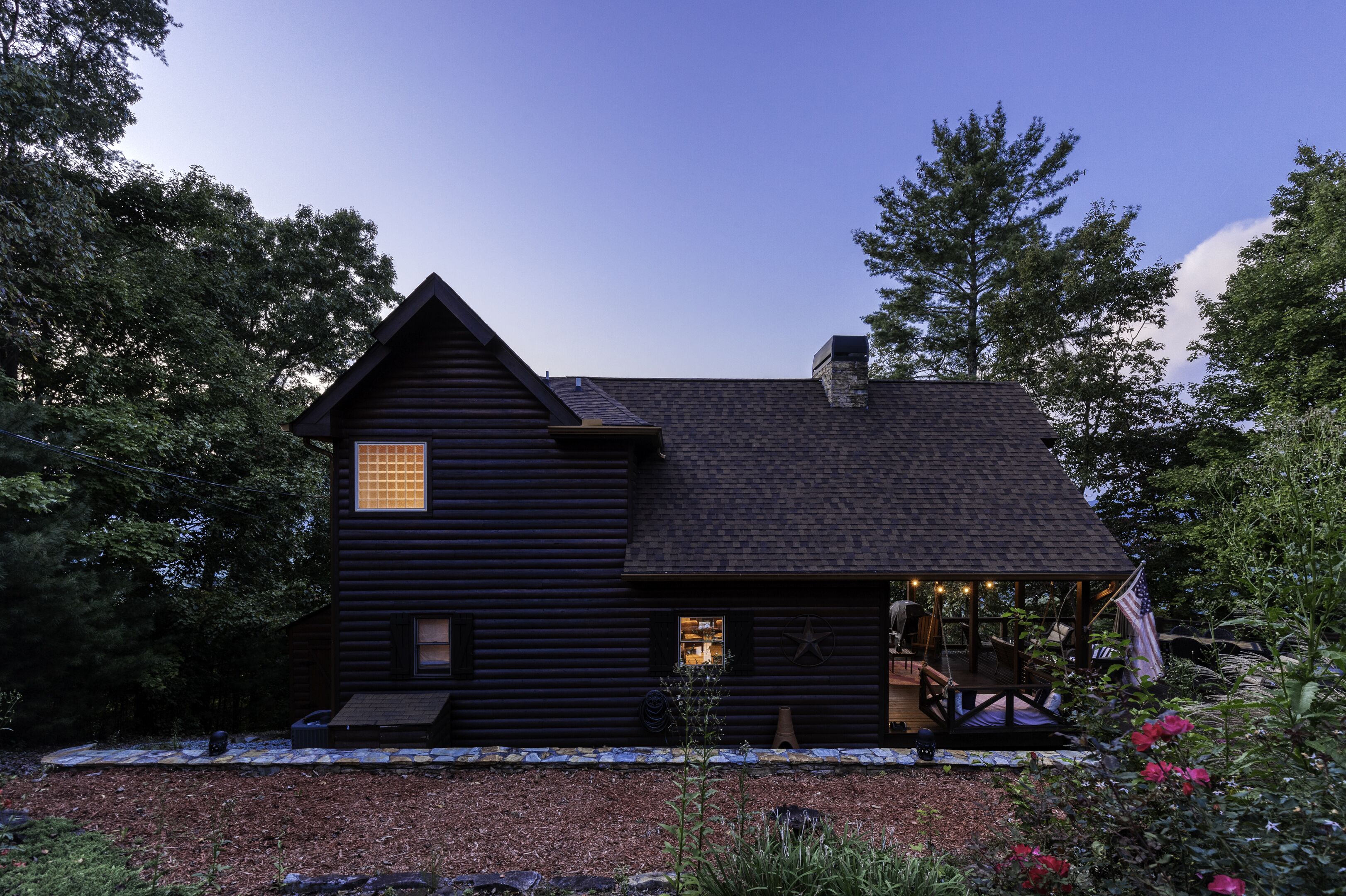 A log cabin with a covered porch, a chimney, and a small window.