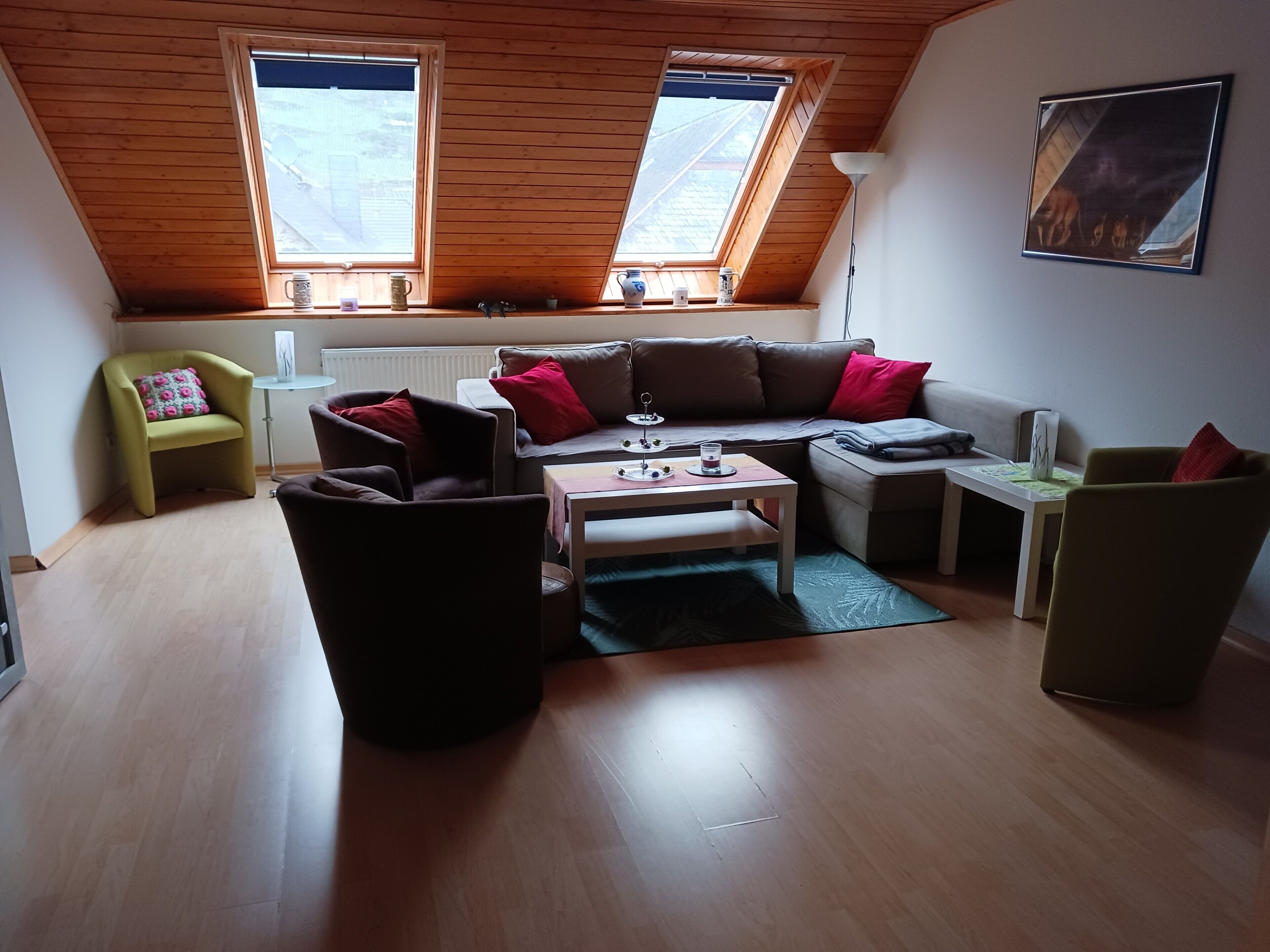 A cozy living room with a wooden ceiling, a sofa, a coffee table, and a small table with a lamp.