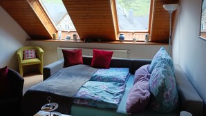 A bedroom with a sloped ceiling, two skylights, a bed with multiple pillows, a chair, and a radiator. - Holiday Apartment "Gersch" with Balcony & Wi-Fi (Traben-Trarbach/Wolf)