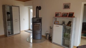 A living room with a wood-burning stove, a glass cabinet with kitchenware, and a door leading to another room. - Holiday Apartment "Gersch" with Balcony & Wi-Fi (Traben-Trarbach/Wolf)