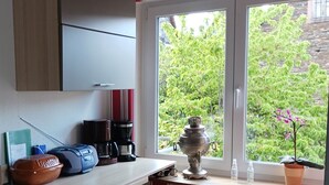 A kitchen with a window, a radiator, a coffee maker, and a potted plant. - Holiday Apartment "Gersch" with Balcony & Wi-Fi (Traben-Trarbach/Wolf)