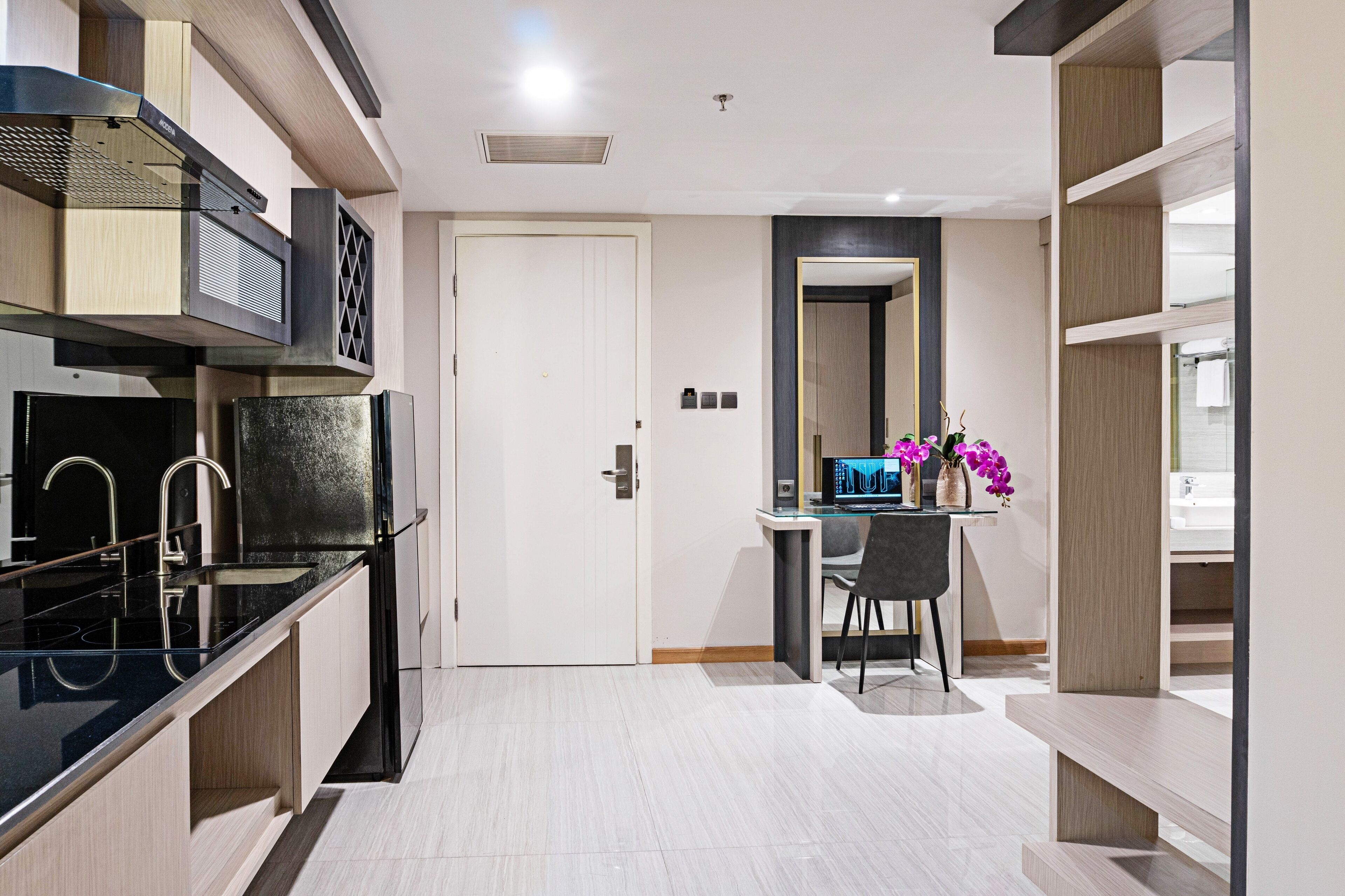 Una cocina moderna con encimera negra, electrodomésticos de acero inoxidable y una puerta blanca.