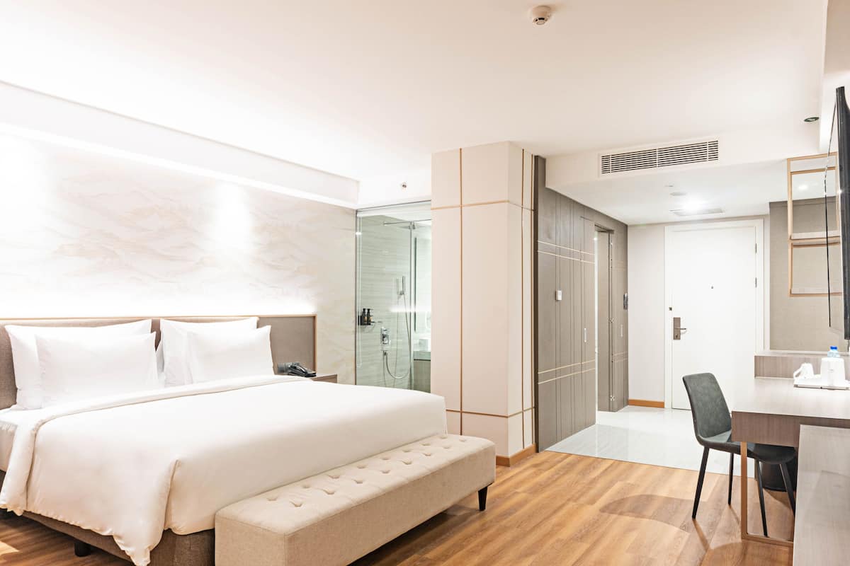 Een moderne hotelkamer met een groot bed, een bureau en een douche.
