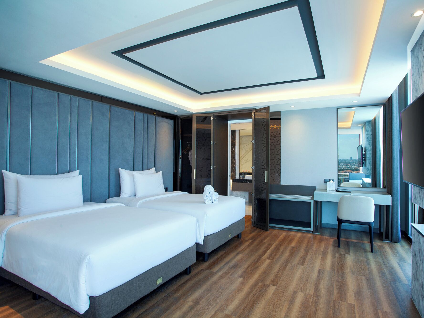 A modern hotel room with a large bed, a desk, and a bathroom visible through an open door.