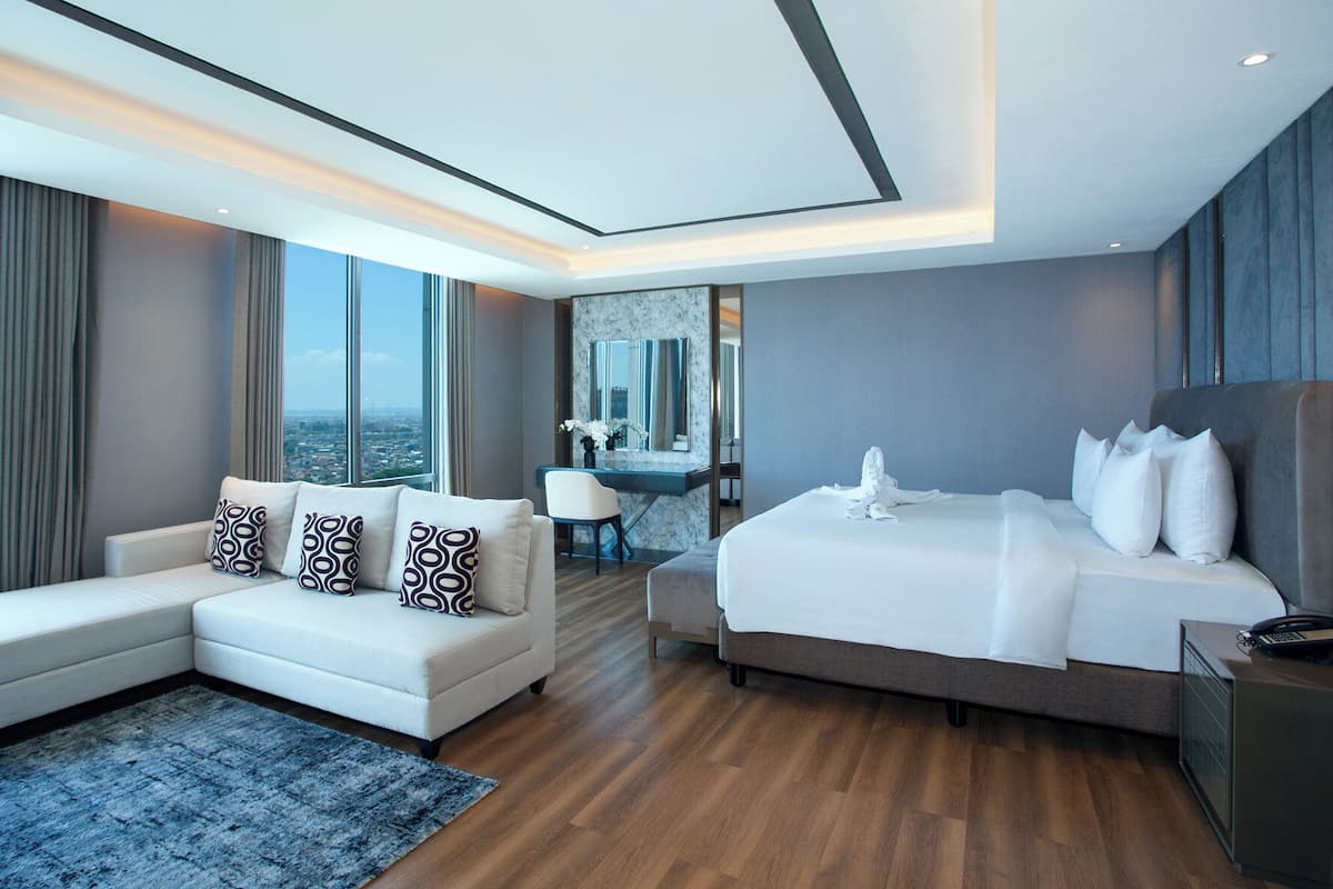 Een moderne hotelkamer met een groot bed, een bank, een bureau en uitzicht op de stad.