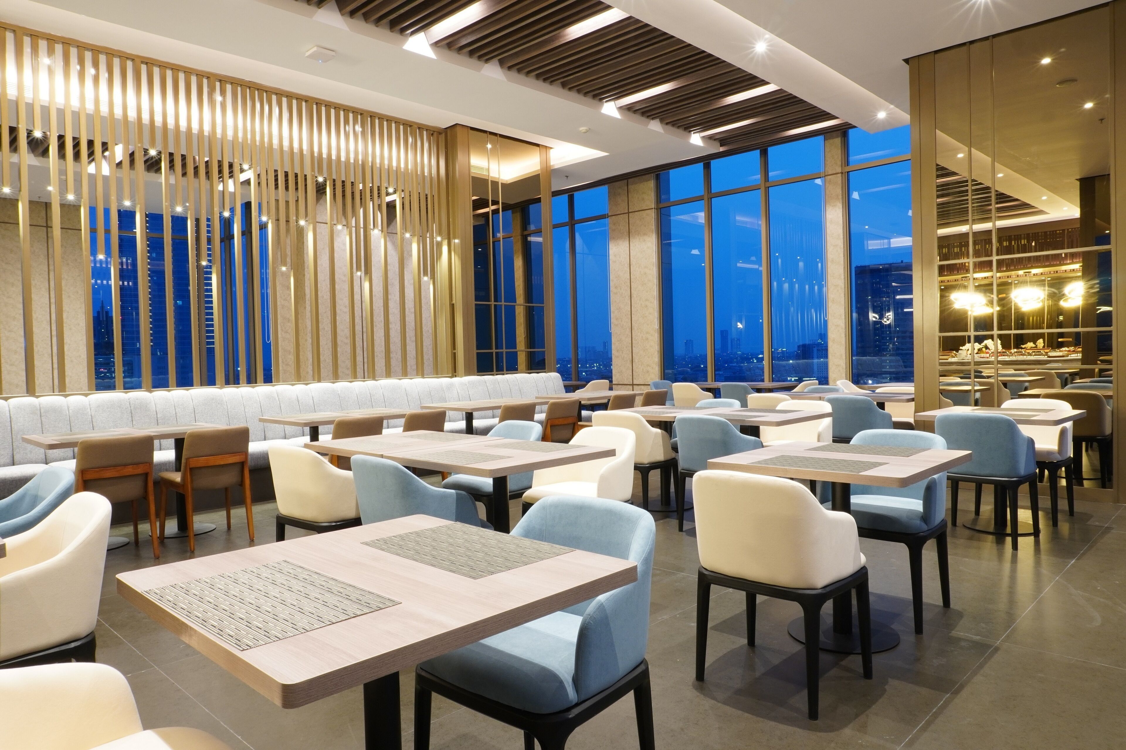 Un restaurante moderno con techos altos, ventanas amplias y vistas a la ciudad.