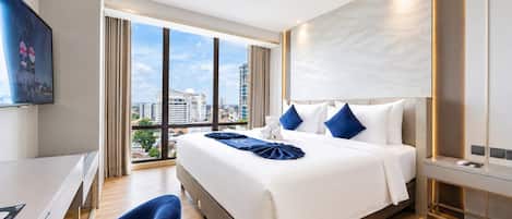A modern hotel room with a large bed, a desk, and a view of the city.