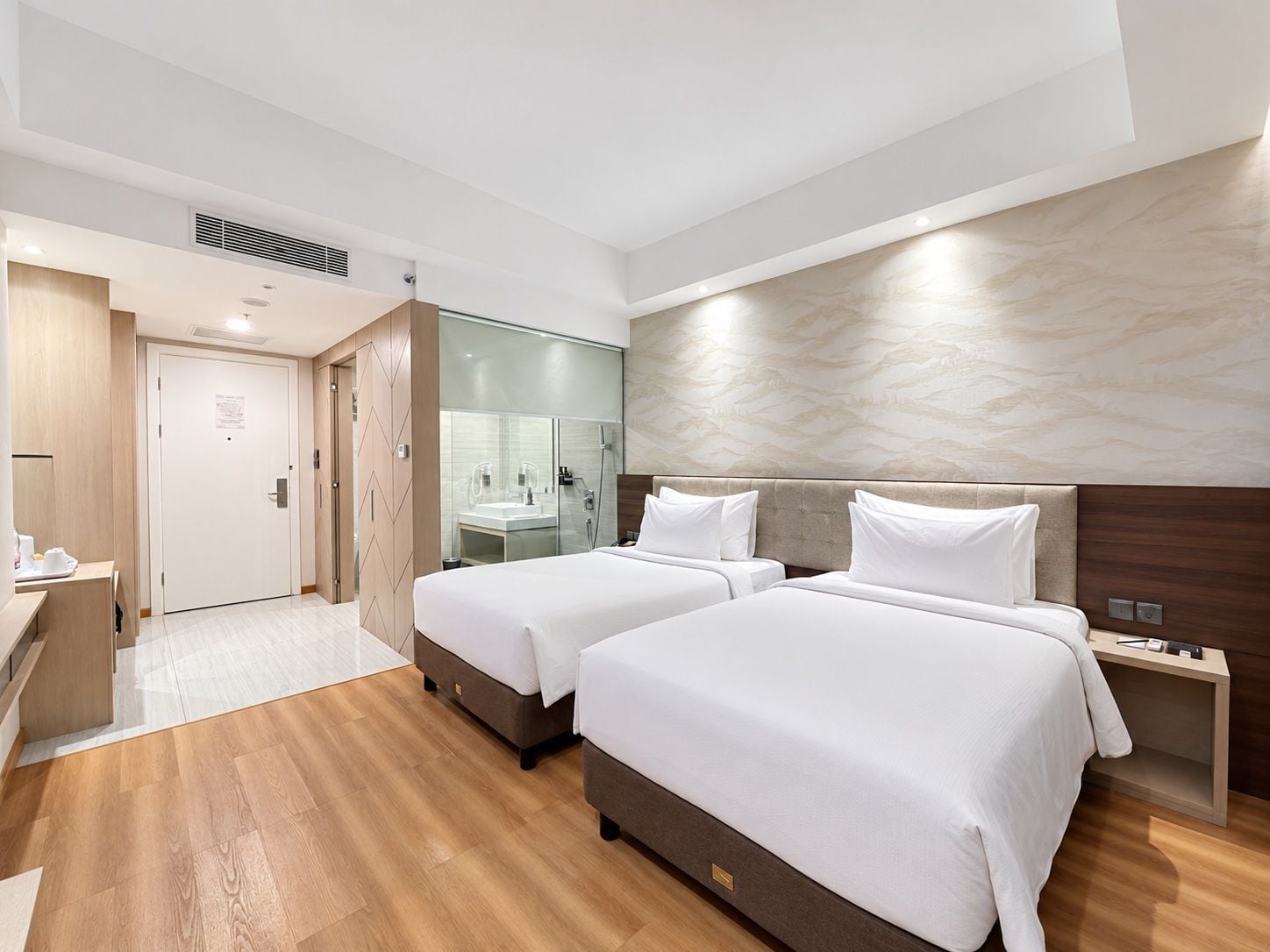 A hotel room with two beds, a bathroom, and a desk.