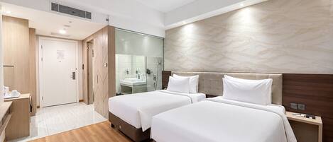 A hotel room with two beds, a bathroom, and a desk.