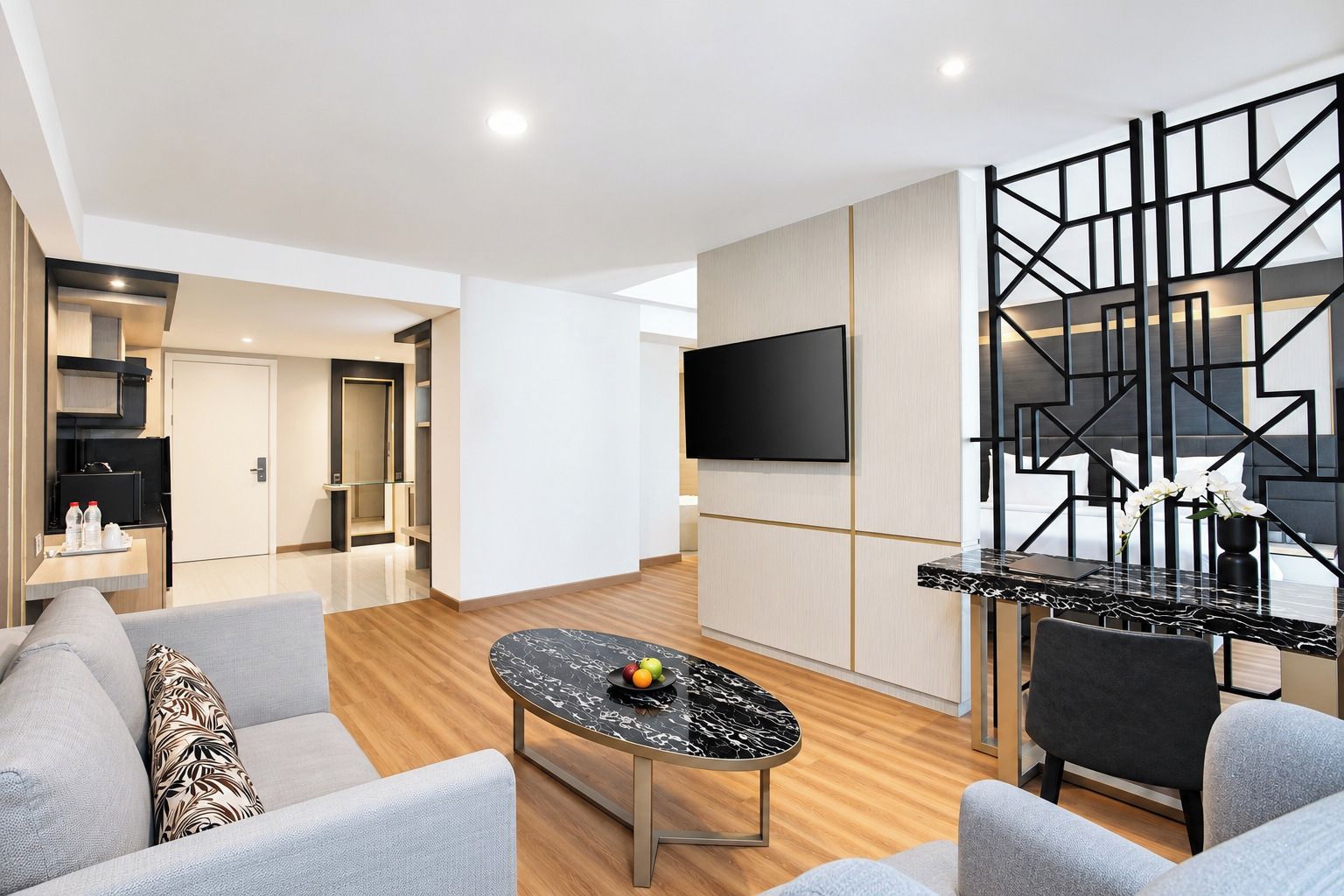 A modern living room with a flat-screen TV, a marble coffee table, and a sofa.