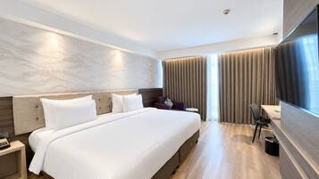 Una habitación de hotel moderna con una cama grande, un escritorio, una silla y un televisor.