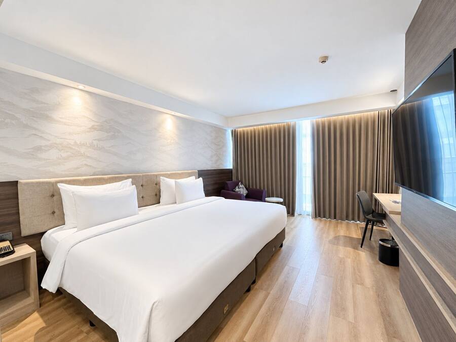 Una habitación de hotel moderna con una cama grande, un escritorio, una silla y un televisor.