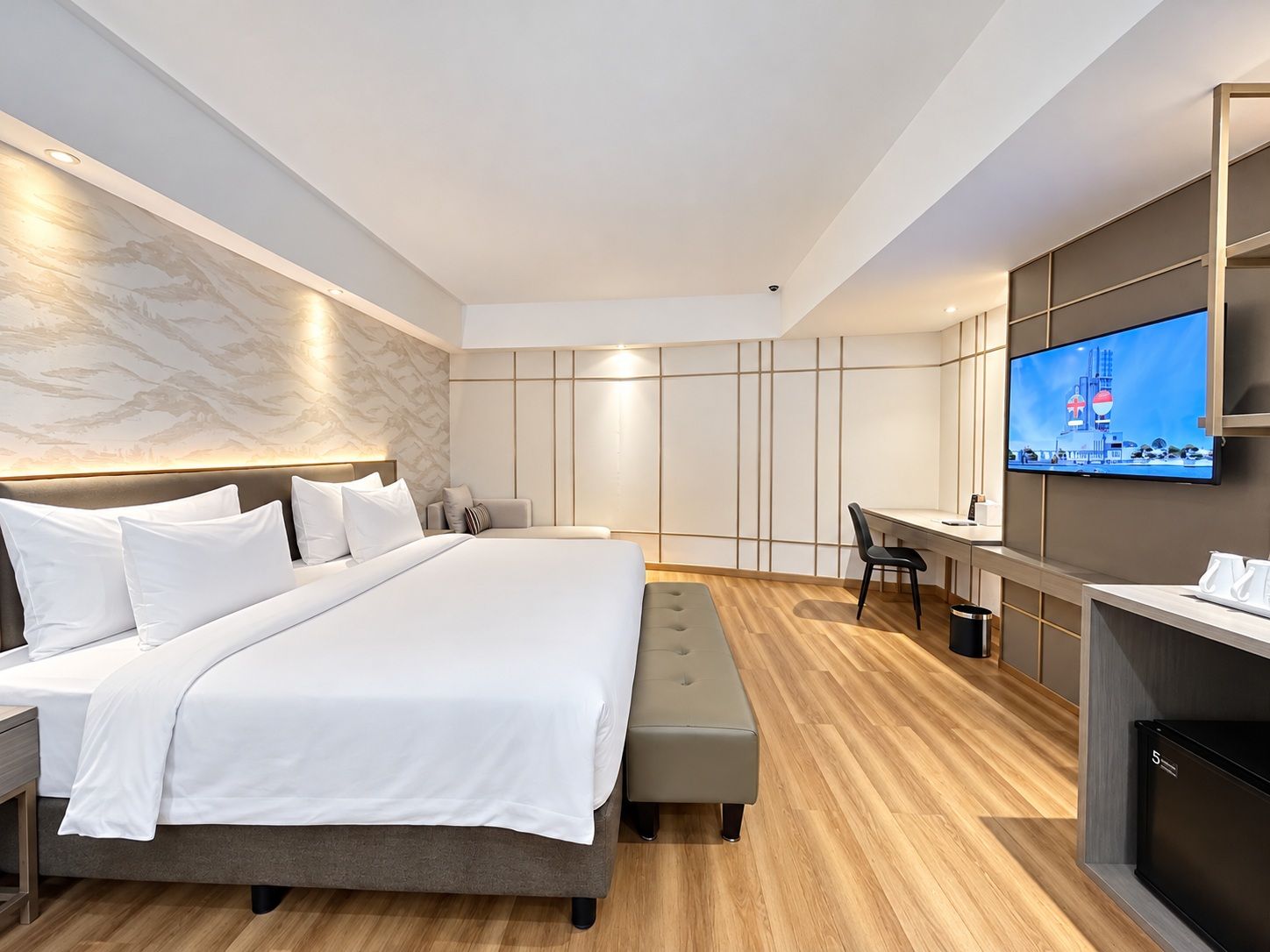 A modern hotel room with a large bed, a desk, and a television.