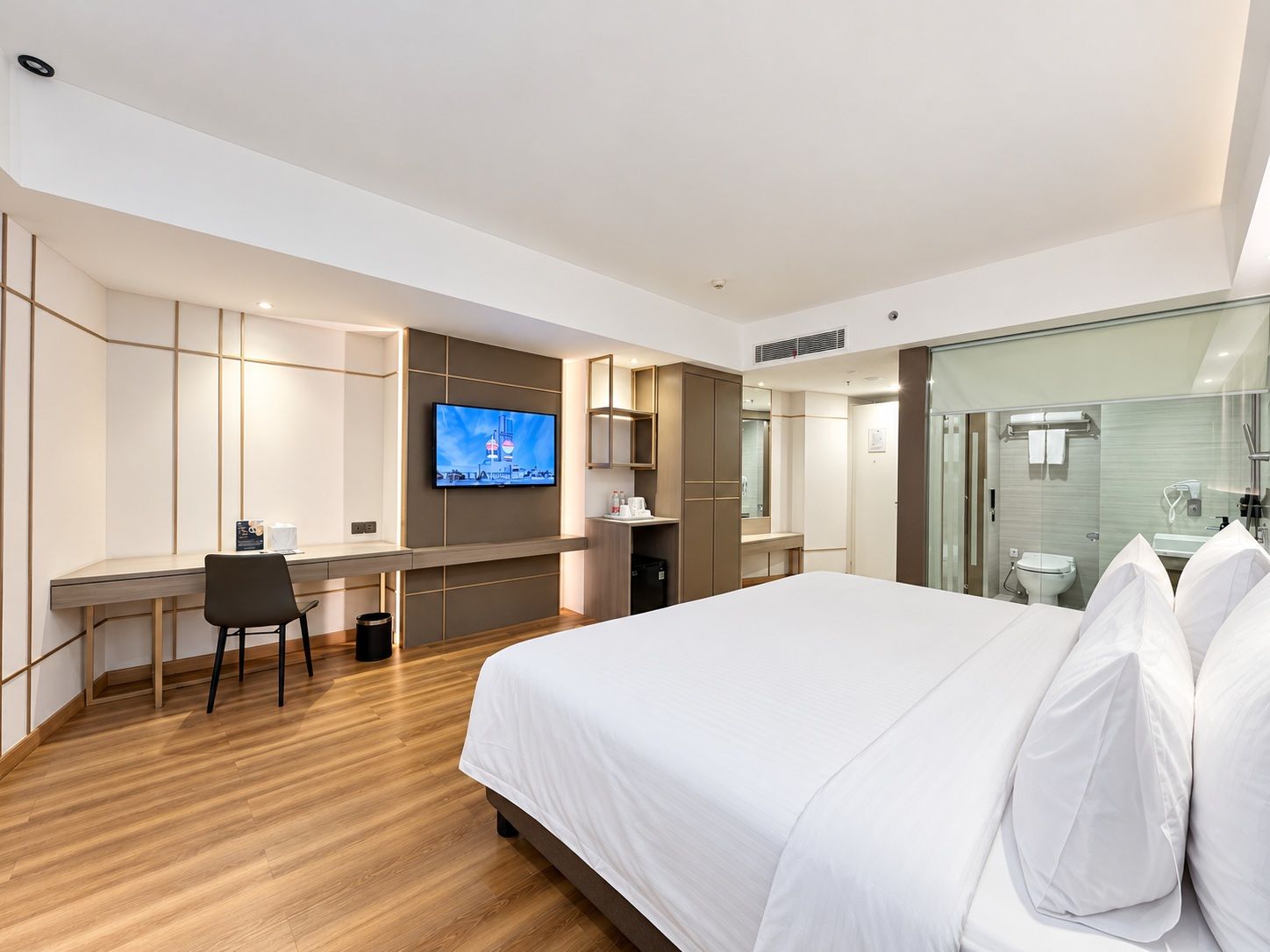 Een hotelkamer met een bed, een bureau met stoel, een televisie en een badkamer met douchecabine.