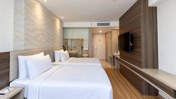 Habitación de hotel moderna con dos camas, televisión y baño con cabina de ducha de vidrio.
