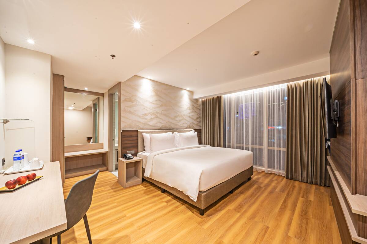 Een moderne hotelkamer met een groot bed, een bureau met stoel, een nachtkastje en een televisie.