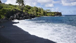A black sand beach with waves, greenery, and a clear sky. - Royal Kahana 301 Remodeled OceanFront 2BD w Ocean Views Pool (Lahaina)