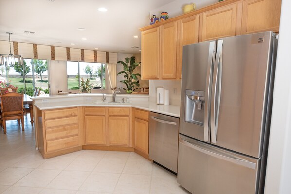 Una cocina moderna con armarios de madera, un refrigerador de acero inoxidable y una isla grande con fregadero.