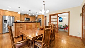 Una cocina amplia con armarios de madera, electrodomésticos de acero inoxidable y una gran mesa de comedor con sillas.