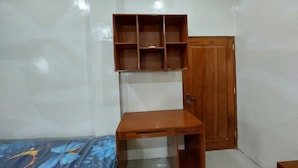 Ein Zimmer mit einem Holztisch, einem Schrank und einer an der Wand befestigten Regaleinheit.