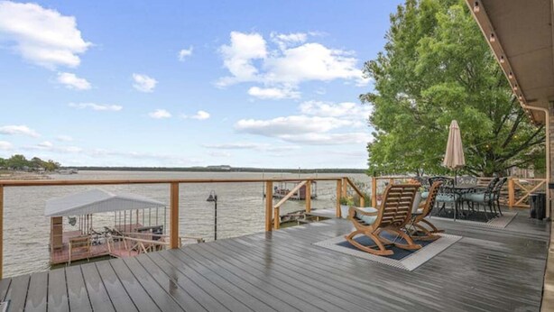 Une terrasse en bois offrant une vue sur l’eau, avec des sièges extérieurs et un espace abrité.