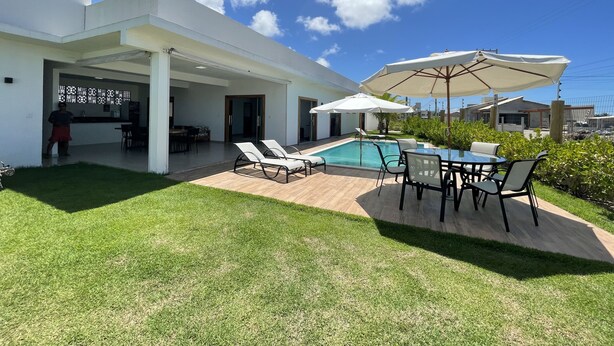 A modern house with a pool, outdoor seating, and a covered patio area. - Casa COMPLETA com Piscina 1 Min da Praia (Prado)