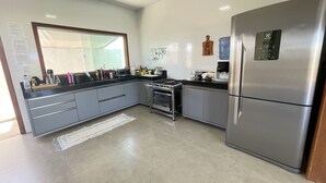 A modern kitchen with grey cabinets, a stainless steel refrigerator, a stove, and a sink. - Casa COMPLETA com Piscina 1 Min da Praia (Prado)