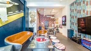 A modern interior with a vintage car display, a large TV, and a brick wall. - Flying Club (Tainan)