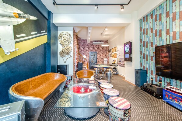 A modern interior with a vintage car display, a large TV, and a brick wall. - Flying Club (Tainan)