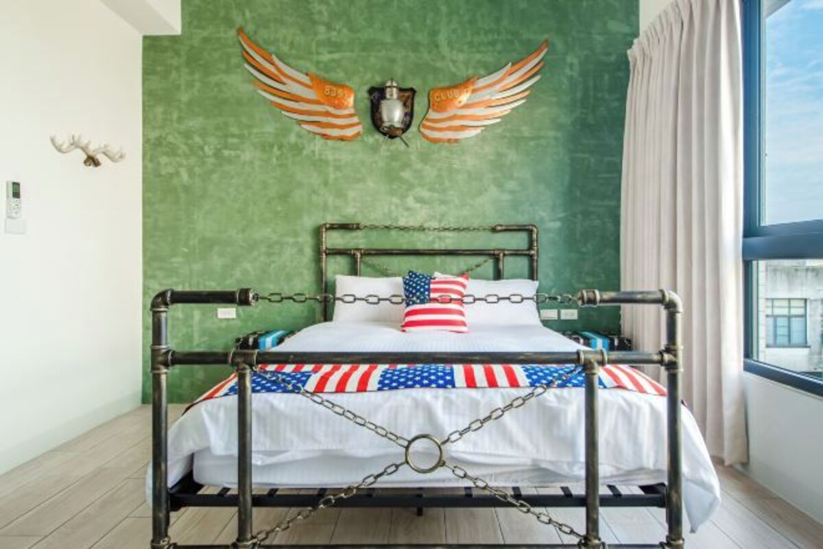 A bed with a metal frame, a flag-patterned bedspread, and an American flag pillow.