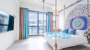 A bedroom with a bed, curtains, a view of buildings, and a decorative wall. - Flying Club (Tainan)