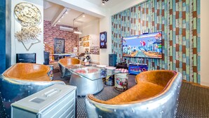 A modern lounge area with unique seating, a large television, and a brick wall. - Flying Club (Tainan)